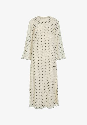 Lange crème jurk met zwarte stippen, ronde halslijn en lange, licht uitlopende mouwen. Voorzien van een zijslit en subtiele zoomdetails.