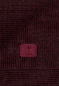 Écharpe en tricot côtelé bordeaux avec une texture douce et un patch rectangulaire en logo présentant un motif floral.
