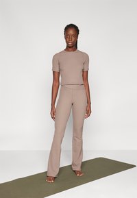 Ensemble de vêtements de sport en deux pièces de couleur brun clair, comprenant un haut à manches courtes et un pantalon évasé taille haute avec une texture côtelée.