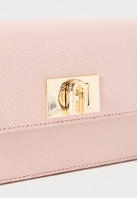 Clutch in pelle rosa chiaro con una finitura texturizzata. Presenta una chiusura dorata con dettaglio del logo. I bordi cuciti conferiscono struttura e resistenza.