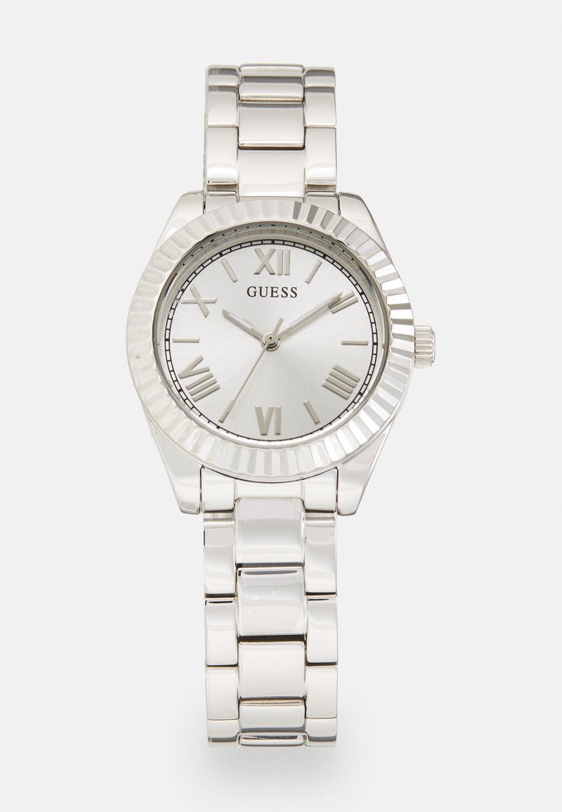 Silver stainless steel wristwatch with a round case, textured bezel, white dial, Roman numerals, and a link bracelet. Brand name "Guess" displayed.