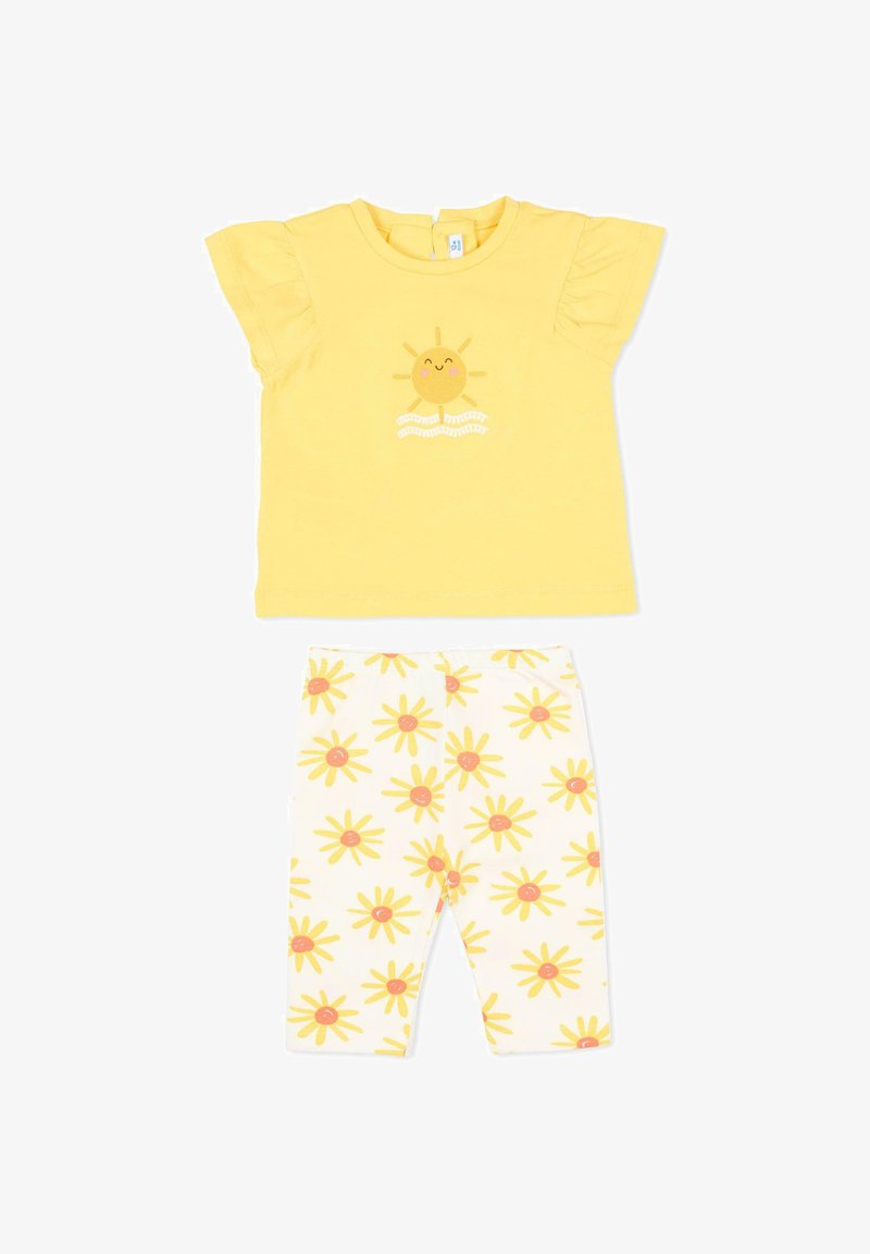 Kortgeleeuwd geel babyshirt met een afbeelding van een lachende zon en witte legging met gele zonpatronen.