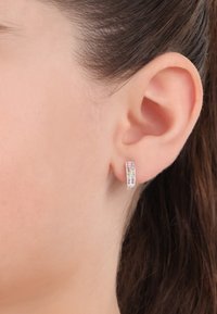 Orecchino a cerchio d'argento con tre file di piccole gemme colorate. Il design è elegante con una finitura lucida, si adatta perfettamente al lobo dell'orecchio.