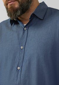Korte mouw knoopshirt van donkerblauw gestreept stof met een puntige kraag en zilveren knopen, met een lichte en gestructureerde uitstraling.