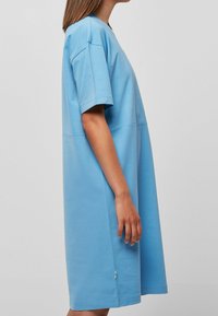 Jasnoniebieska, krótko rękawowa sukienka o luźnym kroju. Wykonana z miękkiego materiału, cechująca się prostą sylwetką i bocznymi rozporkami u dołu.