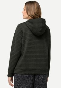 Felpa con cappuccio di colore verde scuro realizzata in materiale testurizzato con una trama a quadrati, dotata di cappuccio e vestibilità rilassata. Presenta maniche lunghe.