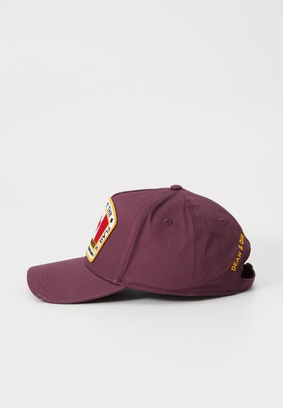 Maroon baseball cap with a rigid brim, featuring a patch on the front and embroidered text on the side. Constructed from cotton fabric.
