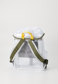 Transparent mesh backpack with green straps, yellow top handle, and a rectangular shape. Notable for its lightweight design and visibility.