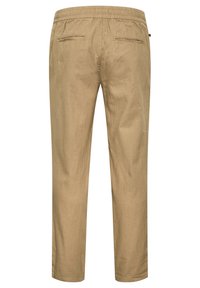 Beige elastische Bundhose mit zwei hinteren Leistentaschen, geraden Beinen und einem kleinen schwarzen Seitenschild an der rechten Seitennaht.