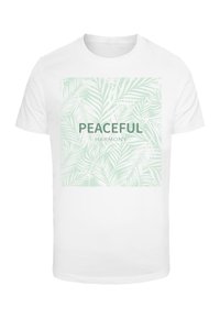 White t-shirt featuring a square mint green graphic with palm leaf patterns. Text in bold: "PEACEFUL" and "HARMONY" below. Short-sleeved design.