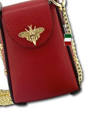 Rode leren handtas met een textuurafwerking, gouden bijembleem op de klep, kettingband en een klein Italiaans vlaggetje charm dat eraan bevestigd is.