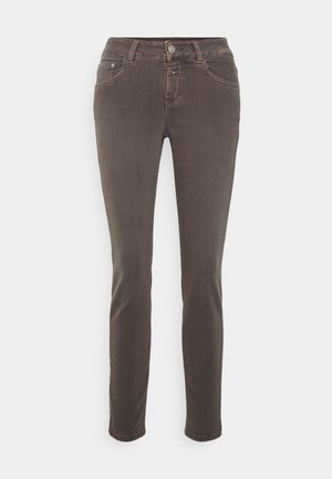 Jean slim marron pour femme avec fermeture à bouton et zip devant, poches avant et arrière, présenté sur un fond clair uni.