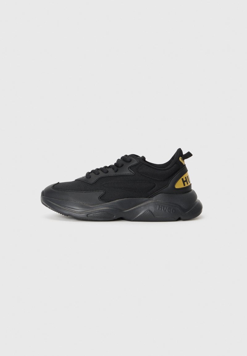 Baskets de sport basses noires avec semelle rembourrée, dessus en mesh et synthétique, et logo jaune "HUGO" sur la languette du talon.