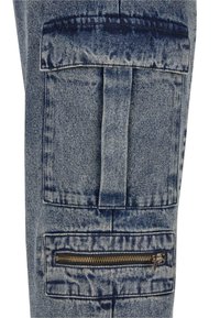 Denim cargo pants feature a large patch pocket and a zippered pocket on the side. Material is a medium blue denim with visible texture.