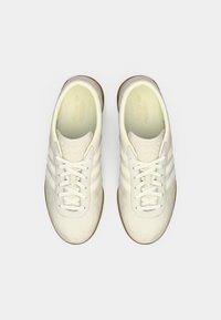 Białe skórzane sneakersy z trzema bocznymi paskami, okrągłym noskiem, sznurowanym fasonem i gumową podeszwą. Gładka tekstura i minimalistyczny styl.