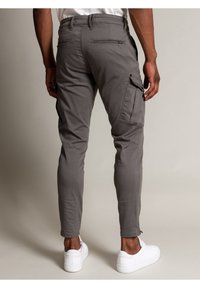 Grijze cargo pants met een slim fit, voorzien van zijzakken en achterzakken met rits, in combinatie met witte sneakers. Gelaagde stof met lichte stiksels.