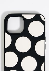 Black phone case featuring large white polka dots. The material appears smooth with rounded edges and a cutout for the camera.