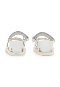 Sandalias de cuero blanco con la parte trasera abierta, que presentan suaves acentos en gris y detalles recortados. Suela plana, diseño minimalista y correas ajustables.
