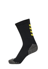Sort sok med ribbet design, der har en grå hæl og tå, samt tre lodrette gule striber på siden. Fremstillet af et struktureret materiale.