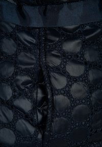 Granatowa pikowana tkanina z okrągłymi wzorami i teksturowaną koronkową nakładką, wykończona plisowanym paskiem w talii dla dodatkowego detalu.