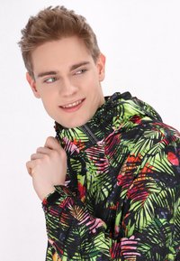 Jachetă neagră cu un model vibrant de vegetație tropicală în nuanțe de verde, roșu și roz. Dispune de un guler înalt și manșete ajustabile. Material ușor.