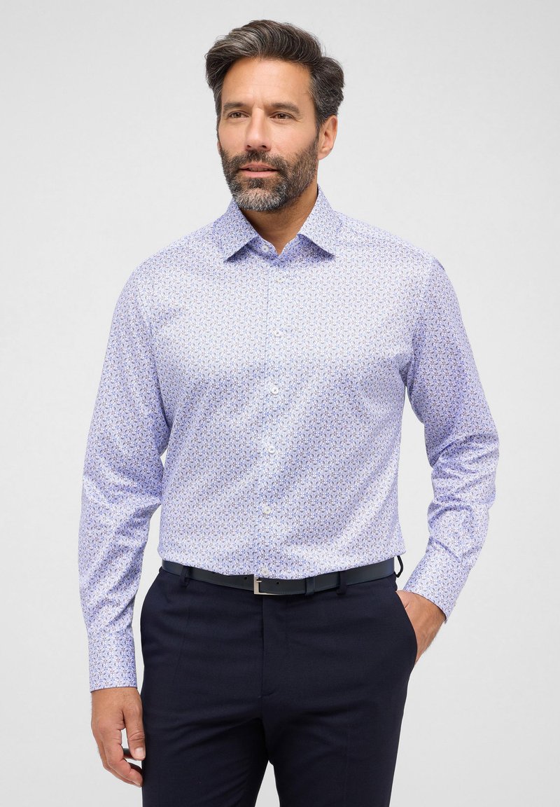 Camicia azzurro chiaro con un piccolo motivo floreale, maniche lunghe e colletto standard, abbinata a pantaloni scuri e una cintura nera.