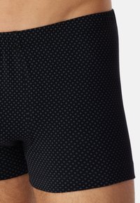 Svarta boxershorts med ett litet blått diamantmönster, tillverkade av ett mjukt tyg, med elastisk midja och figursydd design.