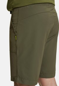 Shorts da esterno color verde oliva con una texture liscia, dotati di una tasca laterale e una vestibilità comoda. Rifiniti con dettagli di cucitura discreti.