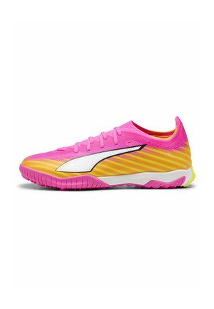 Chaussure de sport basse en dégradé rose et jaune avec logo latéral blanc, conçue pour le gazon synthétique ou les sports en intérieur avec une semelle texturée.