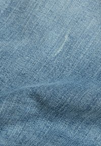 Light blue denim fabric with a slight texture, showcasing a smooth surface and subtle stitching detail. Features a classic twill weave.