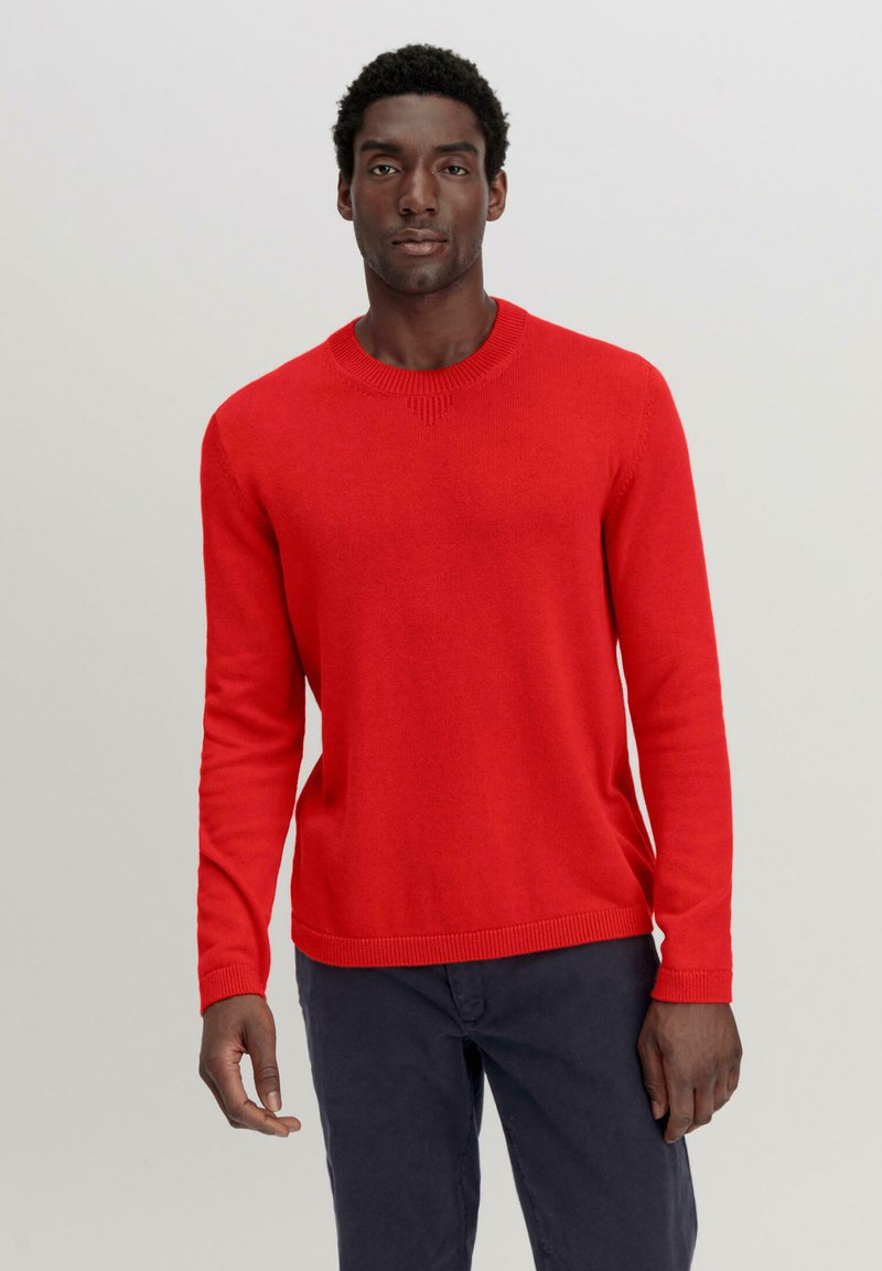 Roter Strickpullover mit langen Ärmeln, Rundhalsausschnitt und gerippten Bündchen. Glatte Textur mit dezenten Details am Halsausschnitt.