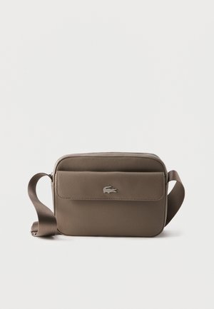 Malá taupe crossbody kabelka s nastaviteľným remienkom a predným vreckom s klopou, na ktorej je strieborné logo krokodíla.