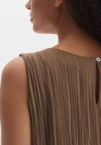 Braunes Faltenkleid mit rundem Halsausschnitt, das auf der Rückseite mit einem Knopfverschluss versehen ist. Weicher Stoff und lockere Passform.