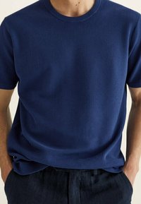 Granatowa krótko rękawowa koszulka typu crewneck o prążkowanej strukturze z luźnym krojem, wykonana z lekkiej dzianiny.