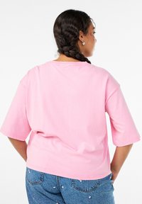 Lyserød bomulds t-shirt med korte ærmer, afslappet pasform, rund halsudskæring og en glat tekstur. Ingen fremtrædende mønstre eller hardware synligt.