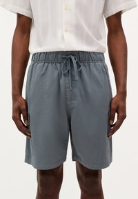 Shorts grii din amestec de bumbac, cu talie elastică și șnur, dotate cu buzunare laterale și o croială lejeră pentru confort.