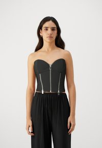 Svart strapless cropped topp laget av glatt stoff, med hjerteformet utringning og to sølvglidelåser foran for lukking.