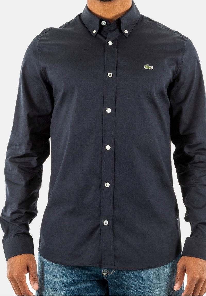 Camicia a maniche lunghe blu navy in cotone, con colletto button-down, bottoni bianchi e un piccolo logo ricamato sul petto.