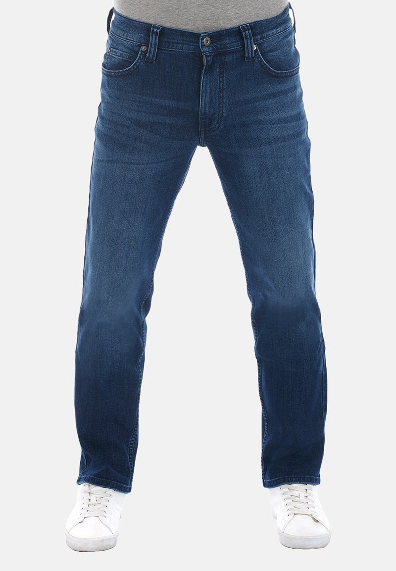 Jeans in denim blu scuro con un design a gamba dritta, stile a cinque tasche, davanti scolorito e chiusura con bottone in metallo, abbinati a sneakers bianche.