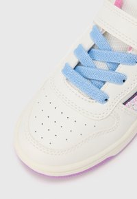 Pantof sportiv din piele albă cu șireturi albastre, accente din plasă și căptușeală roz. Dispune de o zonă perforată în zona degetelor și talpă de cauciuc violet.