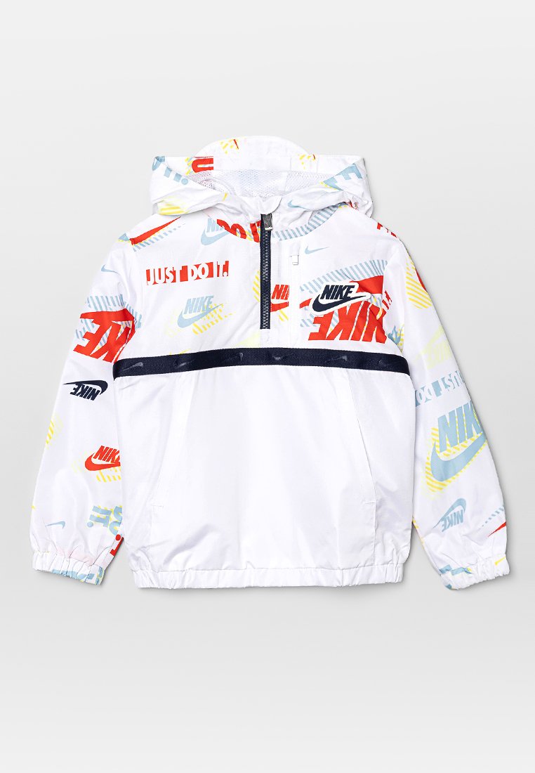 Veste coupe-vent blanche avec des logos et du texte Nike multicolores. Dotée d'une fermeture éclair mi-hauteur à l'avant, d'une capuche et de poignets élastiques. Rayure bleue marine sur la poitrine.