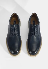 Navyblauwe leren schoenen met een gladde textuur, ronde neus en zes gaatjes voor veters. Crèmekleurige rubberen zool.