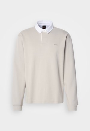 Polo a maniche lunghe color beige chiaro con colletto bianco e patta con bottoni, caratterizzata da un logo sul petto e polsini a costine. Tessuto in cotone liscio.