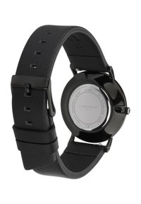 Orologio in pelle nera con cassa rotonda lucida nera, retro in argento e cinturino regolabile con finitura texturizzata e cinque fori di regolazione.