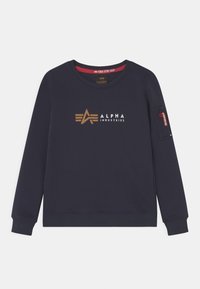 Felpa blu navy con scollo tondo, caratterizzata da un logo dorato "ALPHA INDUSTRIES" e una tasca con zip sulla manica. Texture morbida, polsini a coste.