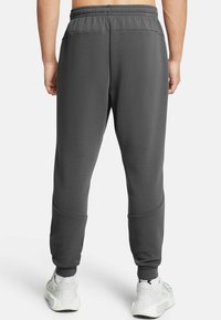 Gray sweatpants in a soft, textured fabric with an elastic waistband and tapered cuffs, featuring contrasting seam details on the legs.