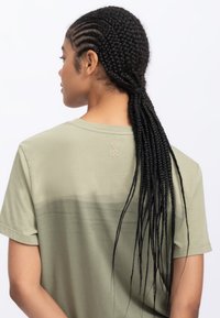 Olive green cotton t-shirt with short sleeves, featuring a subtle gradient pattern and a small scissor logo on the back neckline.