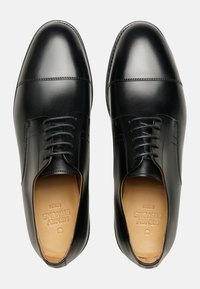 Schwarze Lederhalbschuhe mit einer glatten Oberfläche, runder Spitze, klassischer Schnürung und dezenten Nähdetails. Das Innere ist aus hellbraunem Leder.