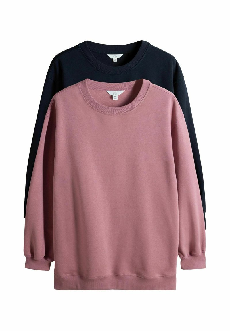 Divas džemperi: viens gaiši rozā, otrs tumši zils. Abiem ir apaļa apkakle, garas piedurknes un mīksta auduma tekstūra.