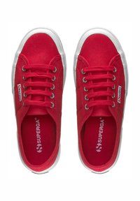 Scarpe da ginnastica in tela rossa con suole e occhielli in gomma bianca. Presentano punta rotonda, design con lacci e logo del marchio sul lato e nella soletta.